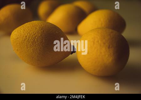 Limoni su tavola bianca con recipiente di frutta sullo sfondo. Foto Stock