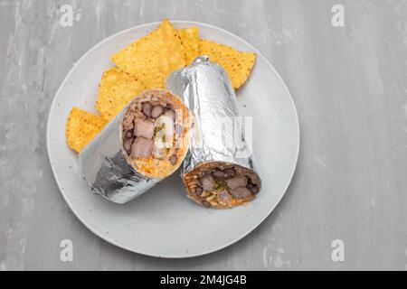 Burrito di manzo messicano su piccolo piatto con patatine nachos sul piatto Foto Stock