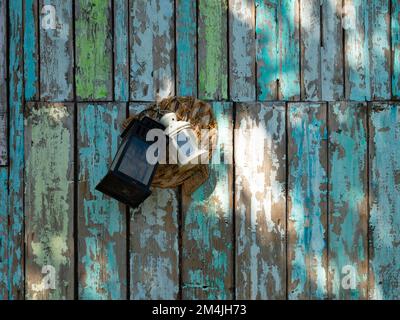 Vecchie tavole con vernice da peeling. Primo piano di lanterne appese al muro Foto Stock