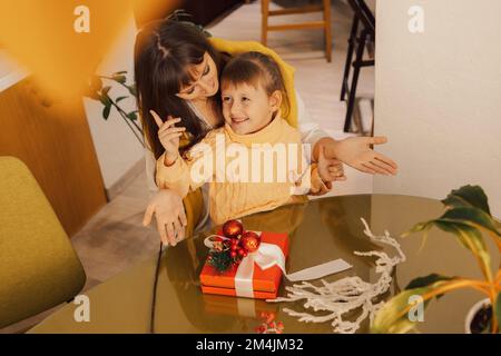Una famiglia felice madre e bambino pacchetto regali di Natale. Stile di vita. Regali per il nuovo anno. Regali di Natale fatti in casa Foto Stock