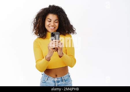 Ritratto di bella ragazza adolescente sorridente, scattare foto, foto su smartphone, puntando a smth durante la registrazione di video sul telefono cellulare Foto Stock