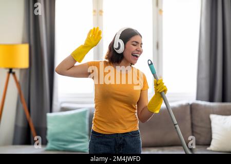 Felice giovane donna araba che ha divertimento mentre fa le faccende domestiche Foto Stock