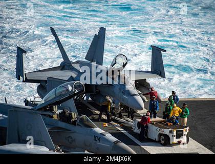 Oceano Pacifico, acque internazionali. 20 dicembre 2022. I marinai della Marina militare statunitense trainano un aereo da combattimento F/A-18E Super Hornet, con i Blue Diamonds of Strike Fighter Squadron 146 in una posizione di mantenimento sul ponte di volo della portaerei di classe Nimitz USS Nimitz operante sull'Oceano Pacifico, il 20 dicembre 2022 in acque internazionali. Credito: MC3 Hannah Kantner/USA Navy/Alamy Live News Foto Stock