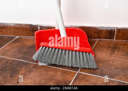 Paletta con scopa su pavimento piastrellato, primo piano Foto Stock