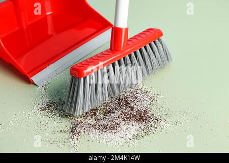 Spazzatura di spazzatura con scopa e paletta su pavimento colorato, primo piano Foto Stock