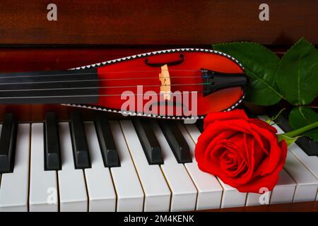 Violino tascabile con rosa rossa su piano Still Life Foto Stock