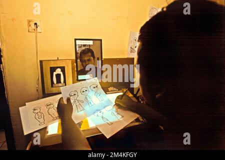 Un uomo sta disegnando personaggi immaginari, una delle attività creative in una casa di produzione affiliata a Daarut Tauhiid e Manajemen Qolbu, fondata dal predicatore religioso islamico indonesiano, KH Abdullah Gymnastiar, situato a Gegerkalong, Bandung, West Java, Indonesia. Gymnastiar (popolarmente noto come AA Gym), Daarut Tauhiid, e Manajemen Qolbu (mq) sono riusciti a intensificare il turismo religioso e le attività economiche nella zona di Gegerkalong a Bandung City. Foto Stock