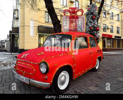 Almaty, Kazakhstan - 18 dicembre 2022: Auto retro rossa con decorazioni per alberi di Natale e un albero di Natale nel tronco. La vettura decorata per selfie Foto Stock