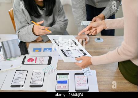 Team di sviluppatori di applicazioni mobili professionali che controllano e testano il loro nuovo prototipo durante la riunione. Coordinamento UI UX e concetto di lavoro di squadra Foto Stock