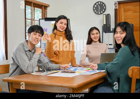 Il team di sviluppatori e progettisti di applicazioni mobili asiatiche della generazione Y è presente alla riunione, sorridendo e guardando la fotocamera. Concetto di team UI UX Foto Stock