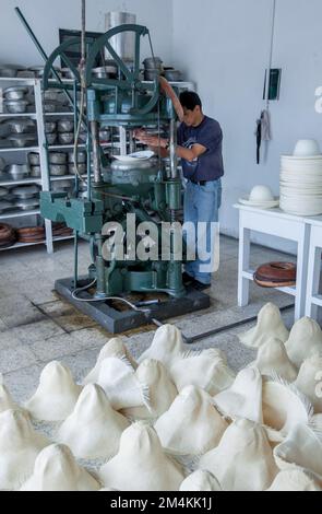 Un operaio che preme un cappello di paglia di toquilla, anche conosciuto come cappello di Panama nella figura ad una fabbrica situata a Cuenca in Ecuador. Foto Stock