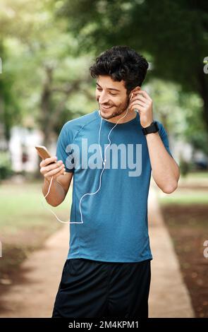 Questa è la mia canzone preferita. un giovane sportivo che ascolta musica mentre si esercita all'aperto. Foto Stock