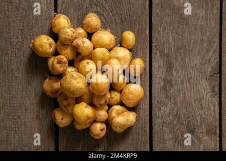 piccole patate pelate dai capelli rossi si trovano su un tavolo di legno da vicino Foto Stock