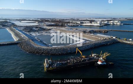 Fehmarn, Germania. 16th Dec, 2022. La fossa di scavo per il portale del tunnel al tunnel della cintura di Fehmarn è visibile accanto al porto di lavoro e al porto dei traghetti di Puttgarden (fotografia aerea scattata con un drone). Il tunnel ferroviario e stradale di 18 km collegherà l'isola di Fehmarn e l'isola danese di Lolland dal 2029. Secondo Femern A/S, il costo è di 7,1 miliardi di euro. Credit: Christian Charisius/dpa/Alamy Live News Foto Stock