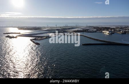 Fehmarn, Germania. 16th Dec, 2022. Accanto al porto di lavoro e al porto dei traghetti di Puttgarden (fotografia aerea scattata con un drone) si trova la fossa di scavo (M) per il portale del tunnel al tunnel di Fehmarnbelt. Il tunnel ferroviario e stradale di 18 km collegherà l'isola di Fehmarn e l'isola danese di Lolland dal 2029. Secondo Femern A/S, il costo è di 7,1 miliardi di euro. Credit: Christian Charisius/dpa/Alamy Live News Foto Stock