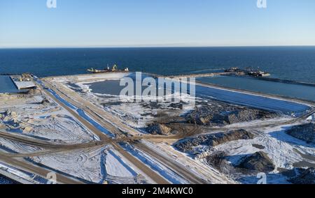 Fehmarn, Germania. 16th Dec, 2022. Accanto al porto di lavoro (l) si può vedere la fossa di scavo per il portale del tunnel che porta al tunnel di Fehmarnbelt vicino a Puttgarden (fotografia aerea scattata con un drone). Il tunnel ferroviario e stradale di 18 km collegherà l'isola di Fehmarn e l'isola danese di Lolland dal 2029. Secondo Femern A/S, il costo è di 7,1 miliardi di euro. Credit: Christian Charisius/dpa/Alamy Live News Foto Stock