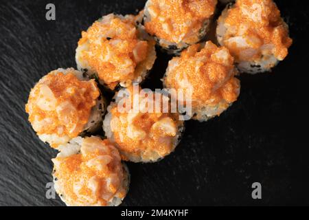 Sushi roll vulcano, California roll con capesante al forno e capra su sfondo di legno scuro, vista dall'alto. Spazio di copia Foto Stock