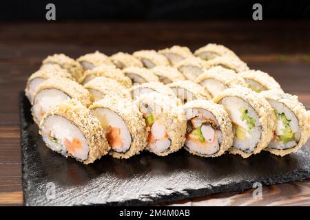 Involtini di sushi fritti caldi con salmone e anguilla. Cucina giapponese. Tempura di sushi fritto caldo. Concetto di menu sushi. Foto Stock