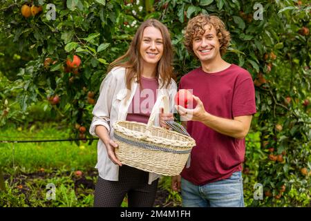 Due gioiosi giardinieri in posa per la macchina fotografica nel frutteto Foto Stock