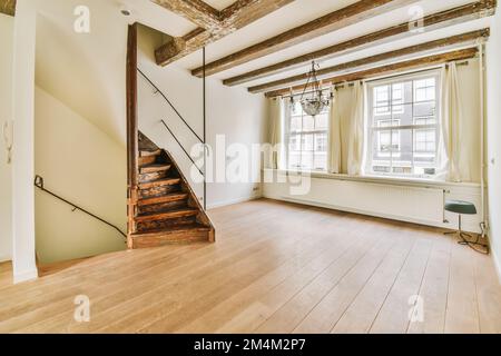 sul corrimano destro è visibile un soggiorno vuoto con pavimento in legno e travi a vista nel soffitto Foto Stock