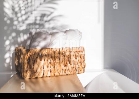 Asciugamani da bagno bianchi arrotolati in tessuto juta cesto su scaffale di legno bagno disposizione stoccaggio Foto Stock