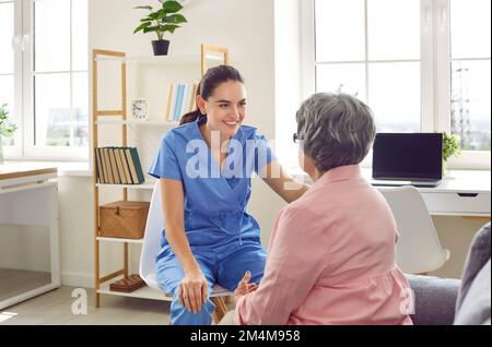 Giovane infermiera o medico che parla con una donna anziana, cercando di sostenerla e rassicurarla Foto Stock