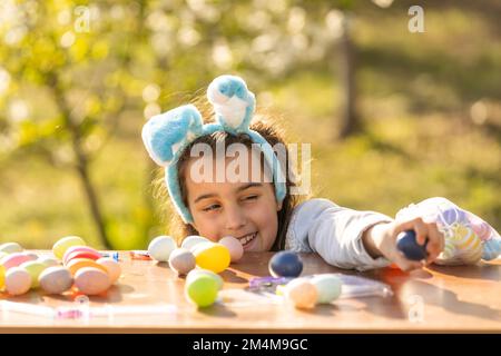 Felice ragazza teen indossare coniglietto orecchie con le uova di Pasqua in giardino Foto Stock