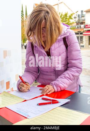 donna che compila un modulo sulla strada. Concetto di petizione della firma Foto Stock