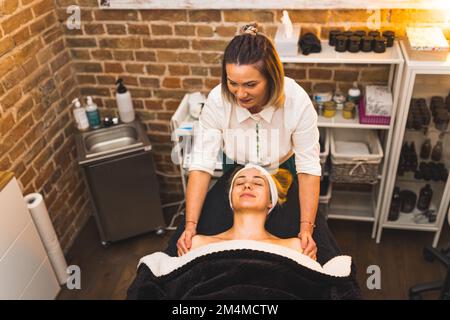 Concetto DI GIORNO SPA. Massaggiatore femminile che dona un massaggio alle spalle e al collo al cliente sul letto SPA. Scatto ad angolo alto. Interno. Spazio di copia. Foto di alta qualità Foto Stock