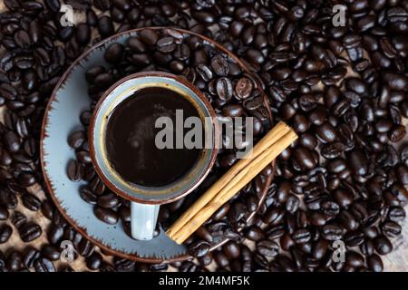 una tazza di caffè con chicchi di caffè arrostiti su sfondo di legno Foto Stock