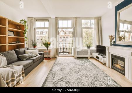 di fronte al divano si trova un soggiorno con pavimento in legno e ampie finestre con vista sulla città Foto Stock