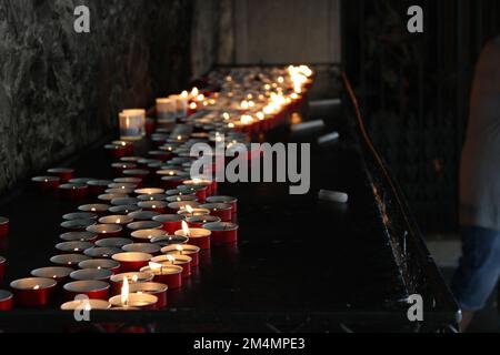 Un tavolo con piccole candele rosse accese in una stanza buia Foto Stock