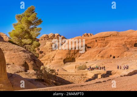 Petra, Giordania - 3 novembre 2022: Persone turisti che camminano lungo canyon di arenaria, formazioni rocciose nel sito patrimonio dell'umanità dell'UNESCO Foto Stock