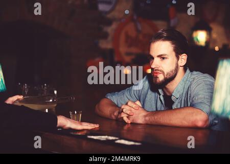L'uomo con la barba siede al bancone del bar sullo sfondo del pub. Foto Stock