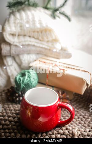 Una serata accogliente a casa per i regali di Natale. una pila di maglioni bianchi sul davanzale vicino alla finestra. Preparazione per bere il tè. A. Foto Stock