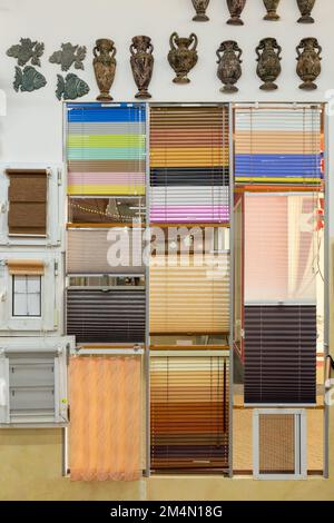 Campioni di tende per finestre nel negozio. Tende in plastica, tende pieghettate, avvolgibili e tende diurne e notturne in negozio. Foto Stock