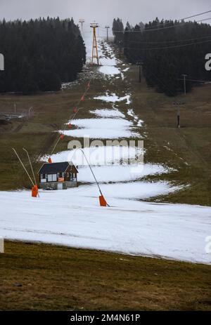 22 dicembre 2022, Sassonia, Oberwiesenthal: Solo i resti di neve si trovano sulla pista sciistica di Fichtelberg. Solo pochi giorni dopo l'inizio, la stagione sciistica in Sassonia è minacciata di una pausa più lunga. Sul Fichtelberg, un solo ascensore era aperto lo stesso giorno. Se continua a piovere così, le operazioni saranno sospese da venerdì (23,12.). Precipitazioni e vento stanno mettendo una tensione sulla copertura di neve sulle piste. Secondo il servizio meteorologico tedesco, rimarrà piovoso durante le giornate di Natale con temperature fino a dieci gradi, e anche in montagna si prevede che rimanga gelo- Foto Stock