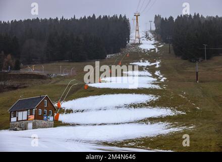 22 dicembre 2022, Sassonia, Oberwiesenthal: Solo i resti di neve si trovano sulla pista sciistica di Fichtelberg. Solo pochi giorni dopo l'inizio, la stagione sciistica in Sassonia è minacciata di una pausa più lunga. Sul Fichtelberg, un solo ascensore era aperto lo stesso giorno. Se continua a piovere così, le operazioni saranno sospese da venerdì (23,12.). Precipitazioni e vento stanno mettendo una tensione sulla copertura di neve sulle piste. Secondo il servizio meteorologico tedesco, rimarrà piovoso durante le giornate di Natale con temperature fino a dieci gradi, e anche in montagna si prevede che rimanga gelo- Foto Stock