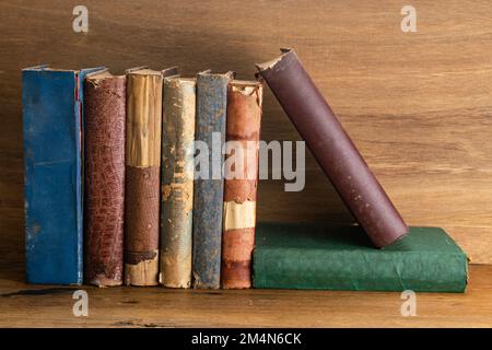 Pila di vecchi libri grungy su sfondo di legno. Libri vecchi e strappati su un tavolo. Foto Stock