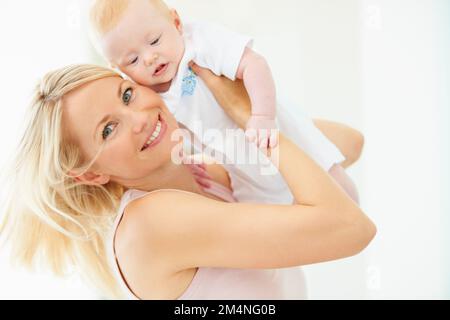 Sentire la gioia di essere madre. Una bella madre che solleva la sua adorabile bambina. Foto Stock