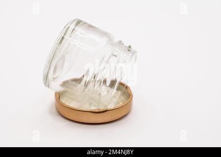 primo piano di un piccolo vaso di vetro trasparente vuoto con un coperchio metallico a vite color bronzo Foto Stock
