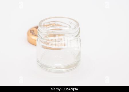 primo piano di un piccolo vaso di vetro trasparente vuoto con un coperchio metallico a vite color bronzo Foto Stock