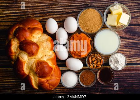 Toast alla zucca alla francese Casserole ingredienti su un tavolo di legno: Pane alla Challah, uova, burro e altri ingredienti per la colazione in casseruola Foto Stock