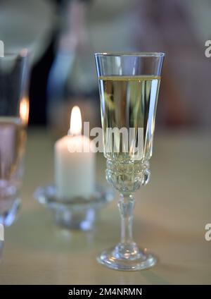 Un bicchiere di champagne e una candela accesa sul tavolo. Messa a fuoco selettiva. Foto Stock