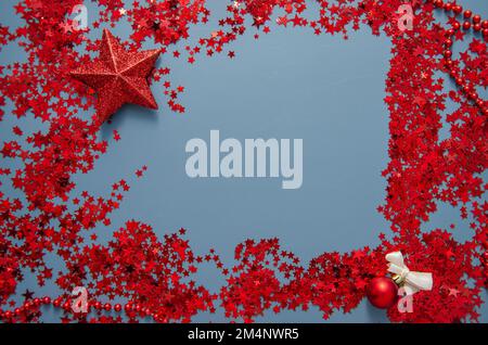 Sfondo natalizio blu con pallina rossa, stella, glitter confetti e decorazioni. Festa di Natale, inverno, Capodanno concetto. Natale ba Foto Stock