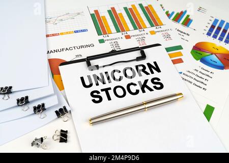 Concetto aziendale. Sulla tabella tra grafici e grafici finanziari si trova una tavoletta con l'iscrizione - Unicorn Stocks Foto Stock