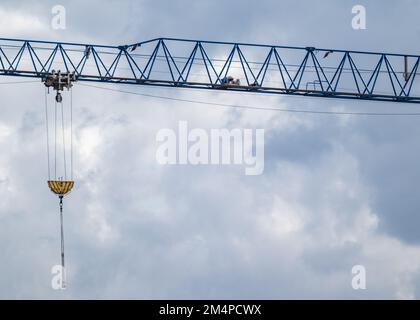 Braccio sporgente blu per gru per il sollevamento di pesi pesanti in cantiere su fondo cielo nuvoloso e panoramico Foto Stock