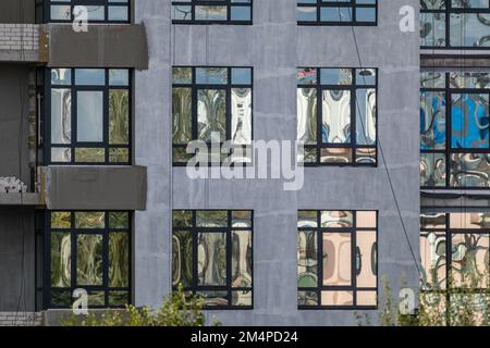 Edificio a piu' piani con facciata grigia con finestre a specchio, cantiere, architettura esterna con dettagli a motivo Foto Stock