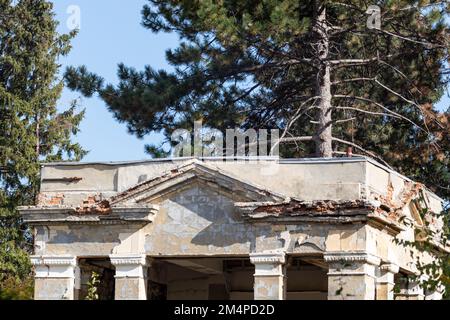 Architettura stalinista facciata d'ingresso del vecchio padiglione dell'edificio sovietico intatto in una giornata di sole con cielo blu e pini Foto Stock