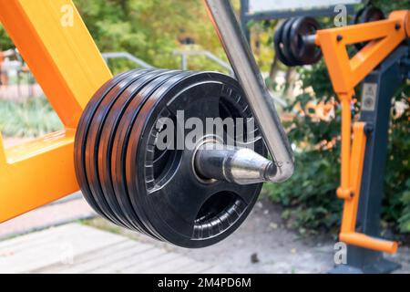 Primo piano con pesi tondi sulle attrezzature per esercizi elettrici. Campo sportivo all'aperto con dettagli per l'allenamento pesi Foto Stock